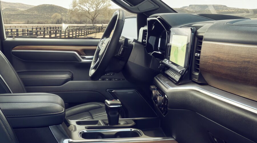 Side view of the luxury cabin inside a 2026 Chevy Silverado High Country featuring open-pore wood trim and premium leather seats at Elkins Chevrolet near Evesham, NJ.