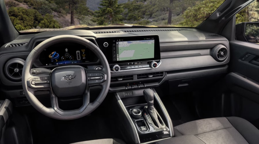 Wide interior view of the 2026 Chevy Colorado dashboard, showing the driver steering wheel, digital instrument panel, and central touchscreen displaying a navigation map evaluated for Cherry Hill area commutes.