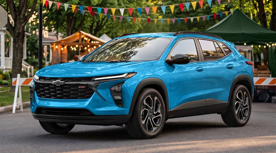 Front three-quarter view of a bright blue 2026 Chevy Trax RS trim parked at a local outdoor event, showcasing the front grille emblem radar sensor and LED lighting suite available at Elkins Chevrolet in Marlton, NJ.