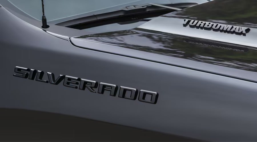 Close-up view of the TurboMax engine hood badge and black Silverado fender emblem on a 2026 Chevy Silverado 1500 at Elkins Chevrolet in Marlton, NJ.