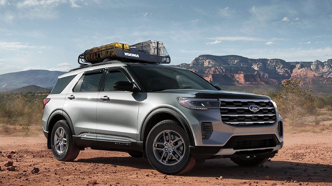 2025 Ford Explorer with cargo on the roof rack parked in the desert with mountains in the background