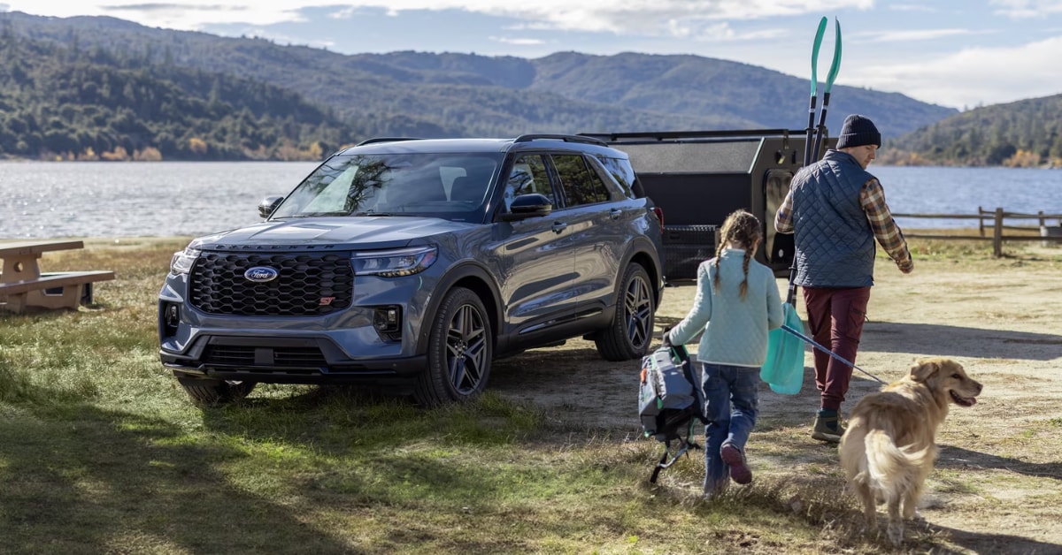 2025 Ford Explorer ST parked by a lake with a family walking nearby