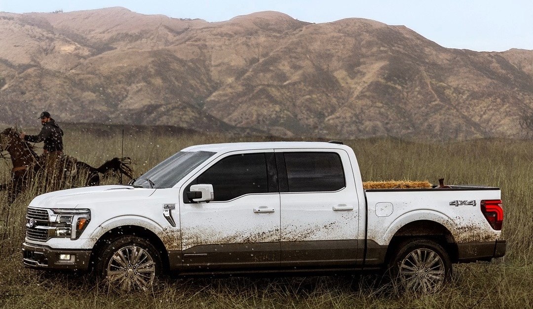 2025 Ford F-150 out in a field with mud on the sides and a cowboy on a horse riding nearby