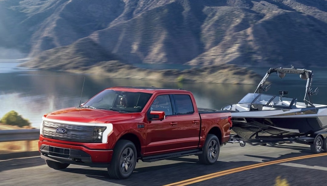 2025 Ford F-150 lightning towing a boat next to a lake