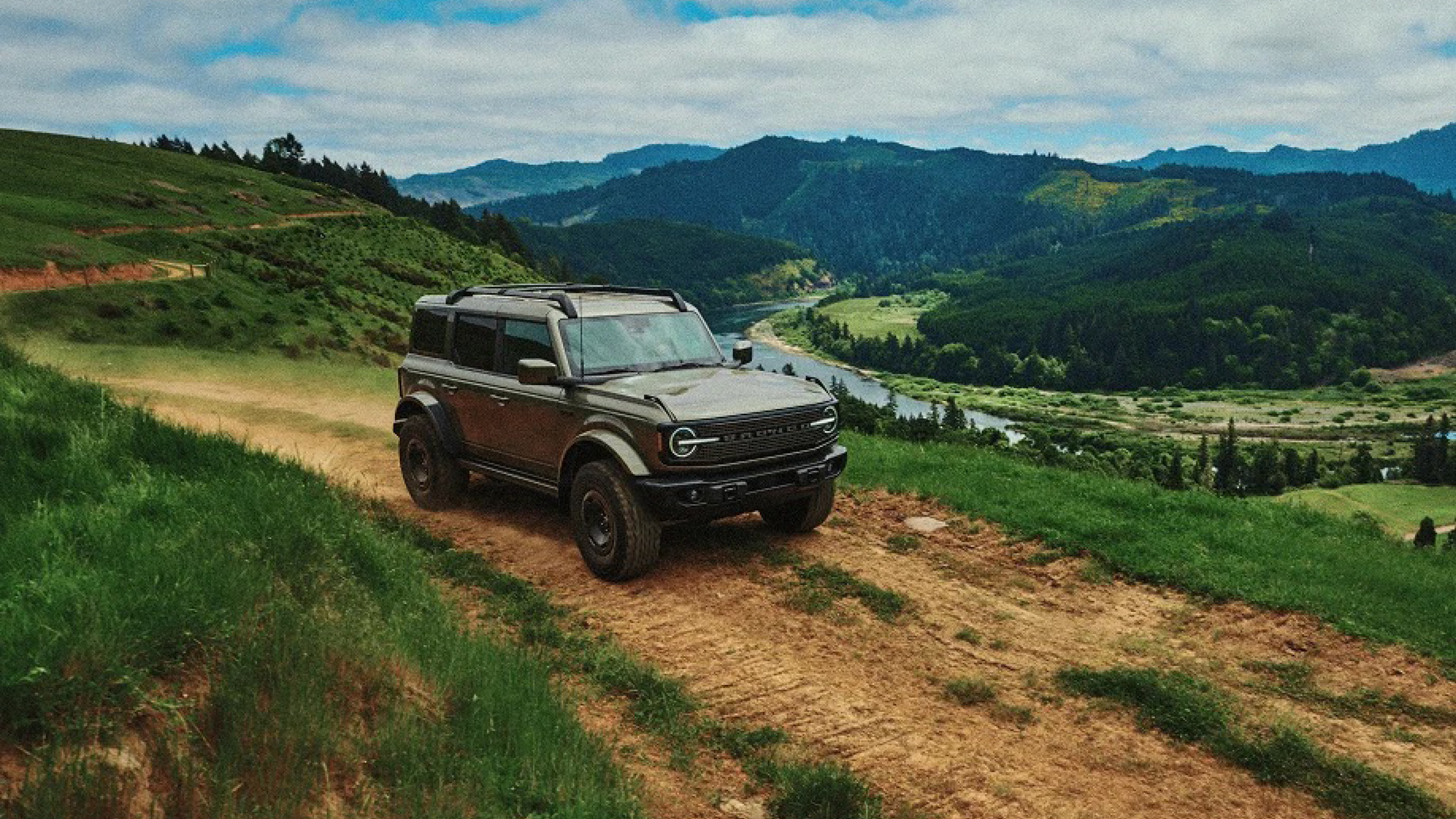 2027 Ford Bronco Filson in Field Green Metallic and Iron Sands Copper Metallic parked at a mountain trailhead in Washington