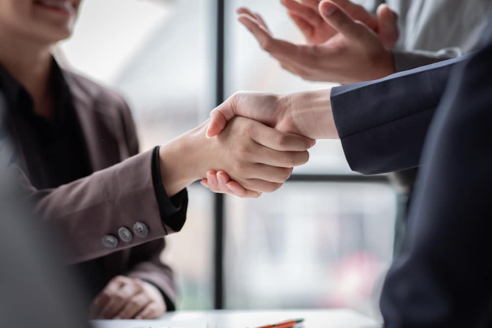 Two people in suit jackets shaking hands