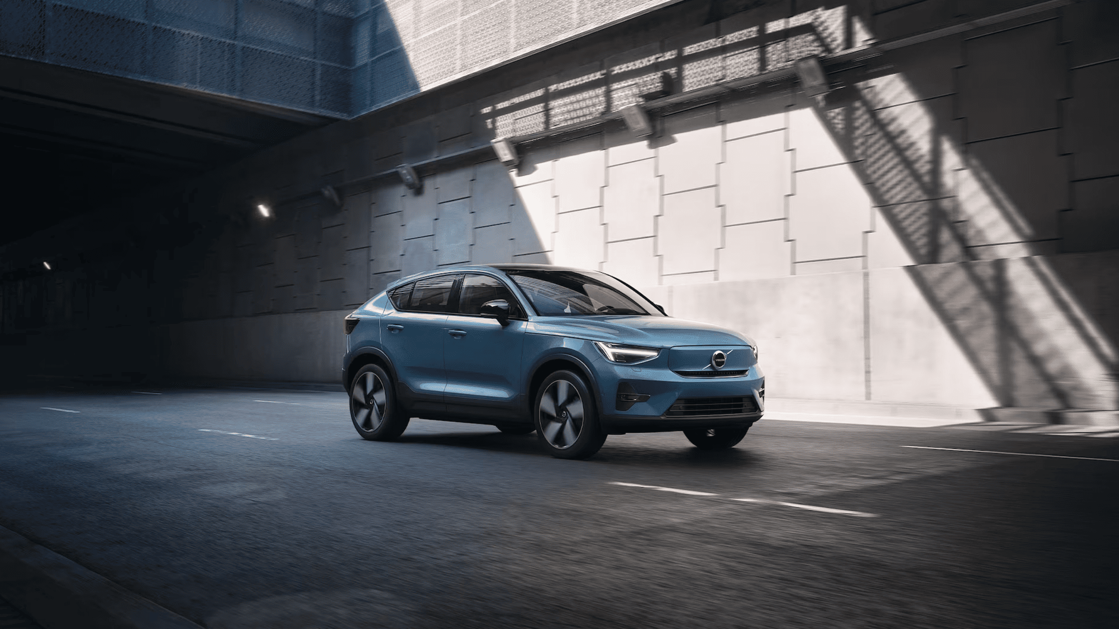 2025 Volvo C40 Recharge electric SUV driving through a modern city tunnel in a dynamic blue finish
