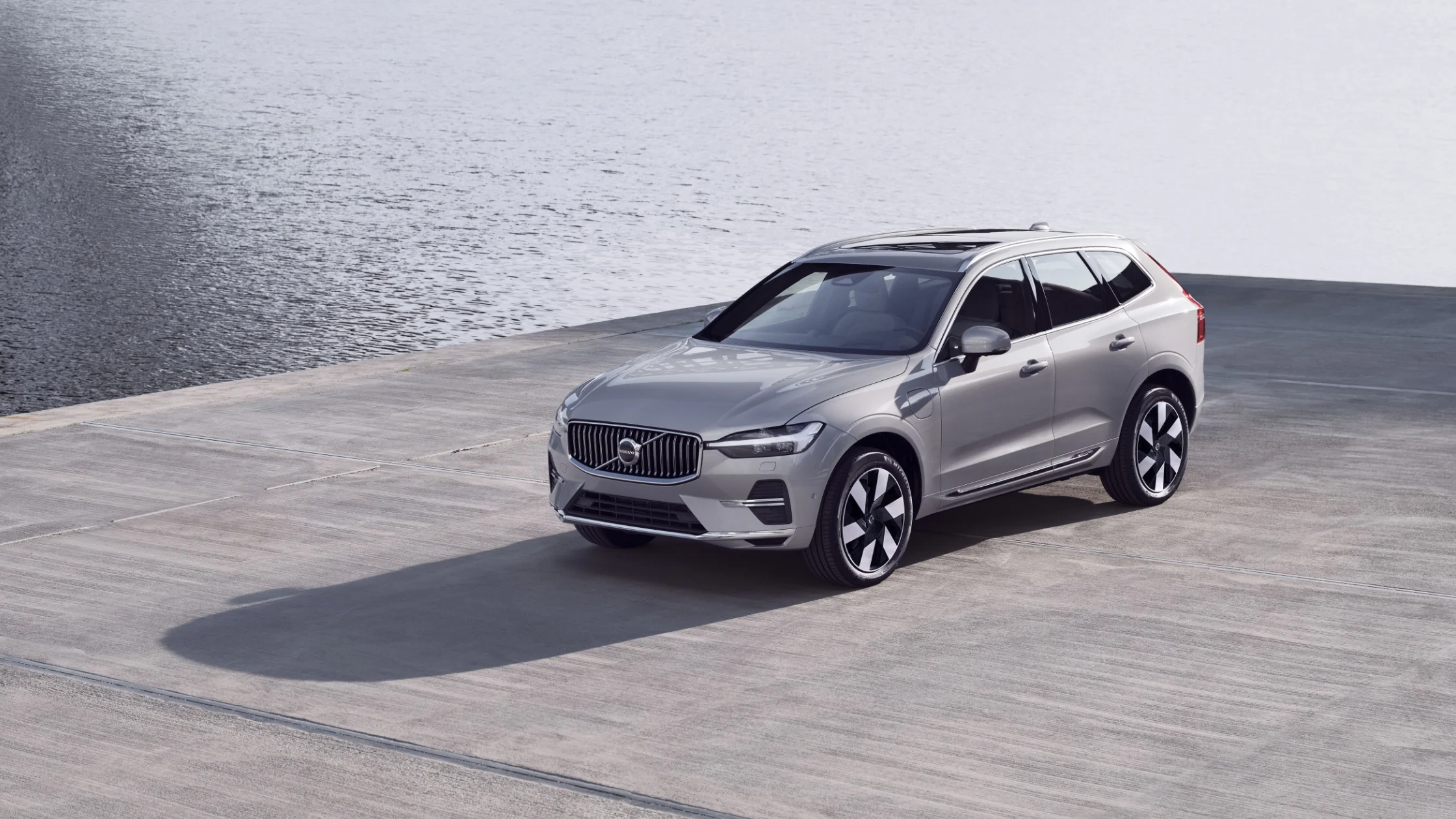 2025 Volvo XC60 Recharge parked near calm water on concrete dock with modern alloy wheels