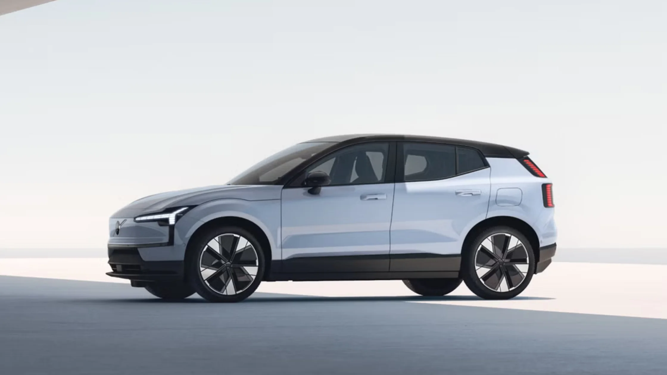 Side profile of a 2025 Volvo EX30 electric SUV in white with black roof and modern styling.