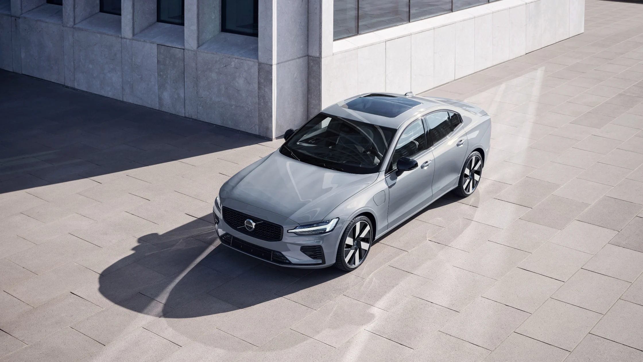 Overhead shot of 2025 Volvo S60 in gray parked near glass building with clean tile surface