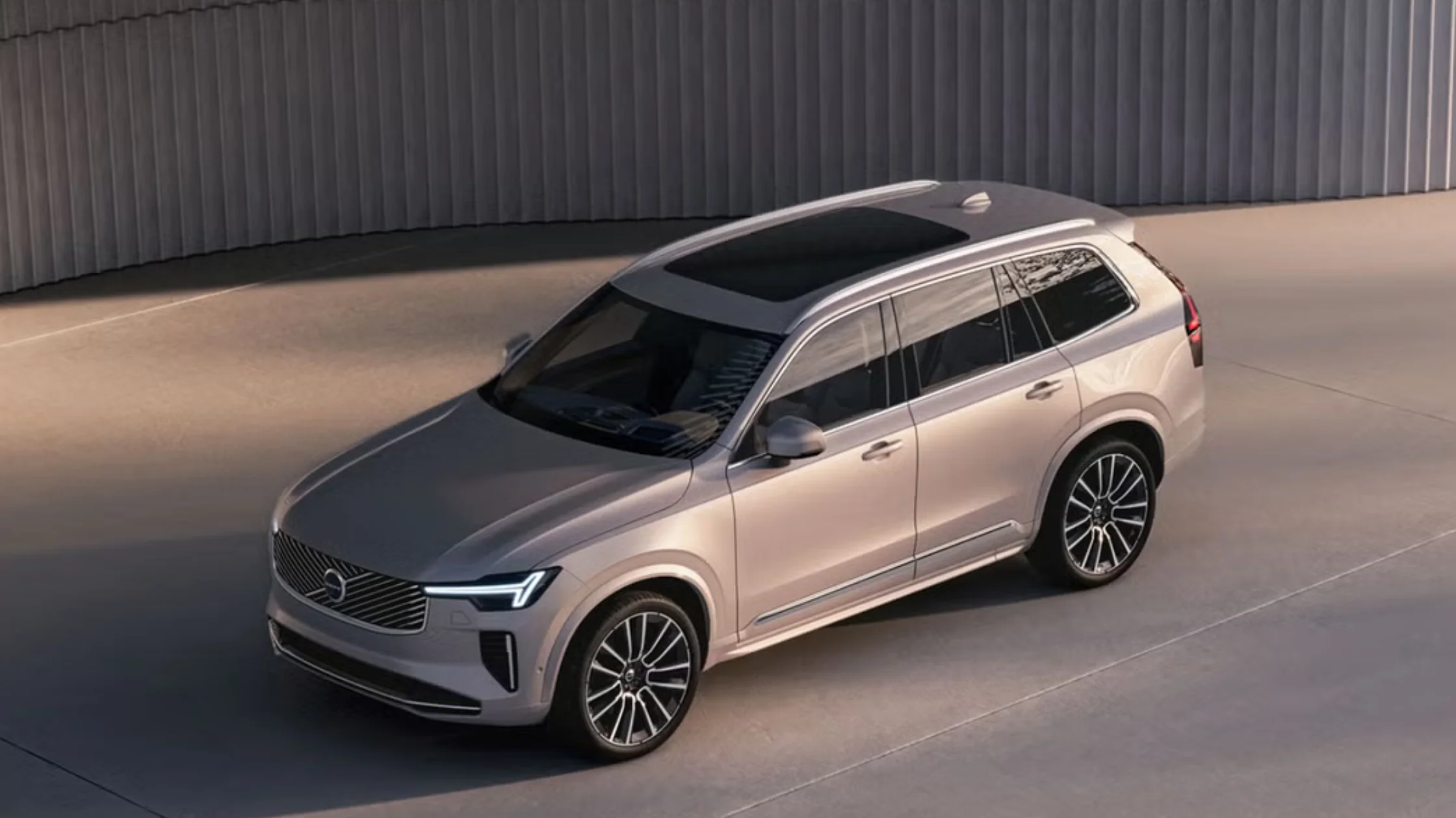 2026 Volvo XC90 midsize luxury SUV in silver, elevated three-quarter exterior view with panoramic roof