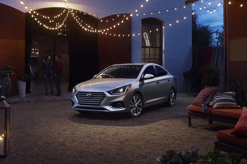 Silver Hyundai Accent parked under streamer lights