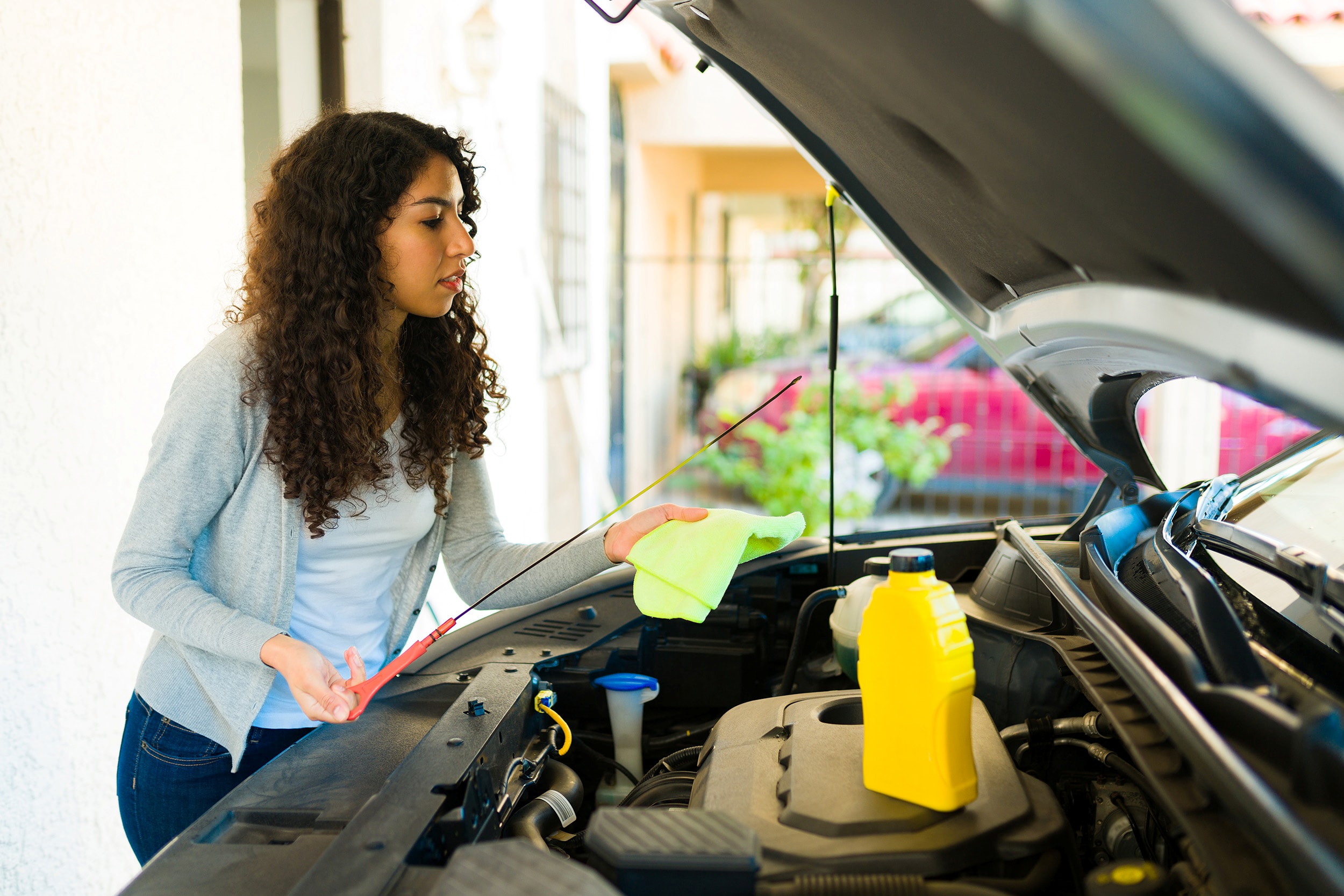 woman checking the oil dipstick in a car