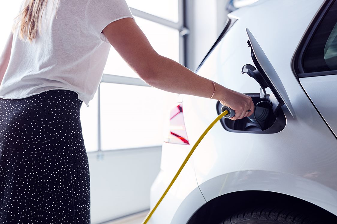 Woman charging an electric vehicle at home