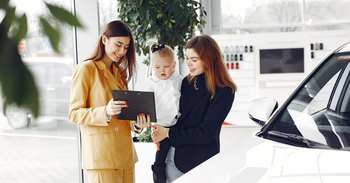 Dealer and a woman with a baby, reviewing paperwork