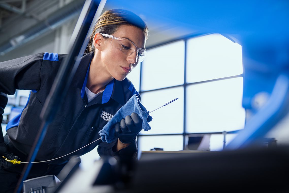 Woman checking a Cadillac engine oil dipstick