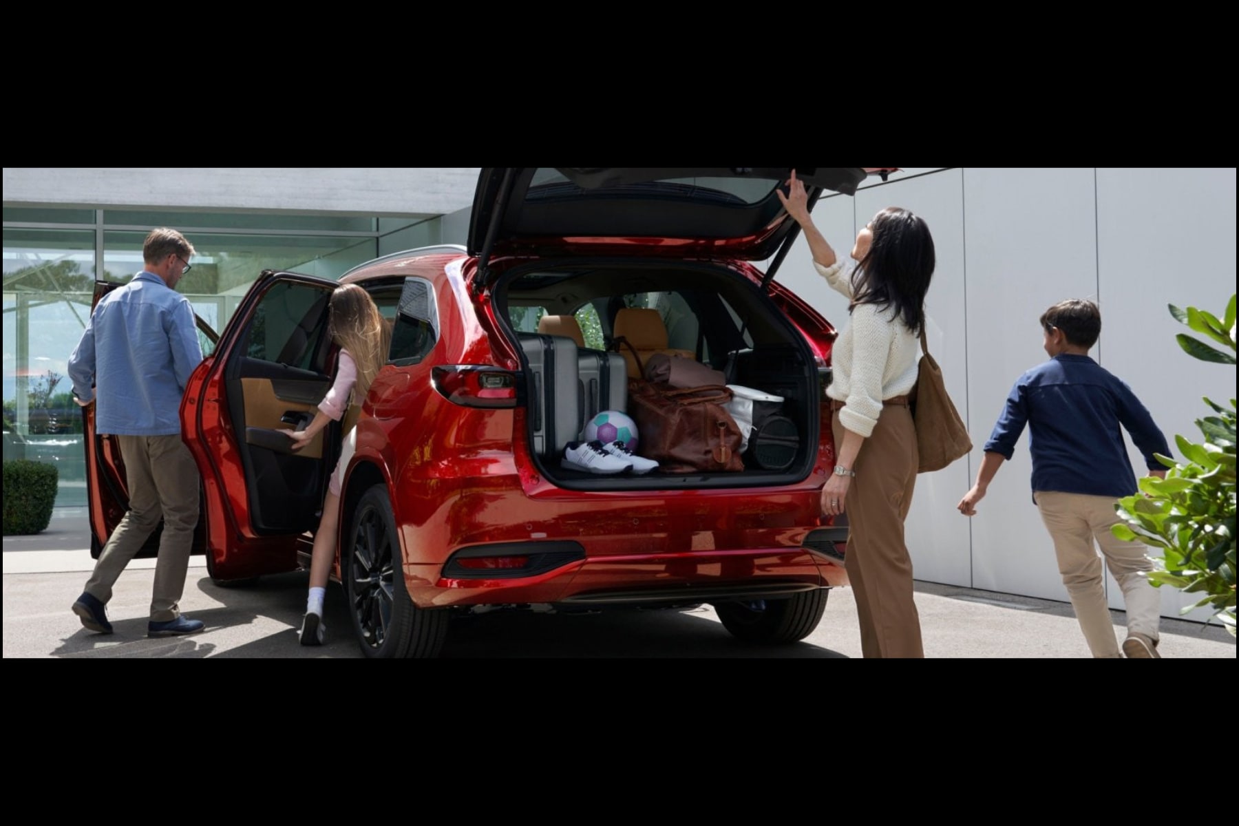 Family packing into a red Mazda SUV