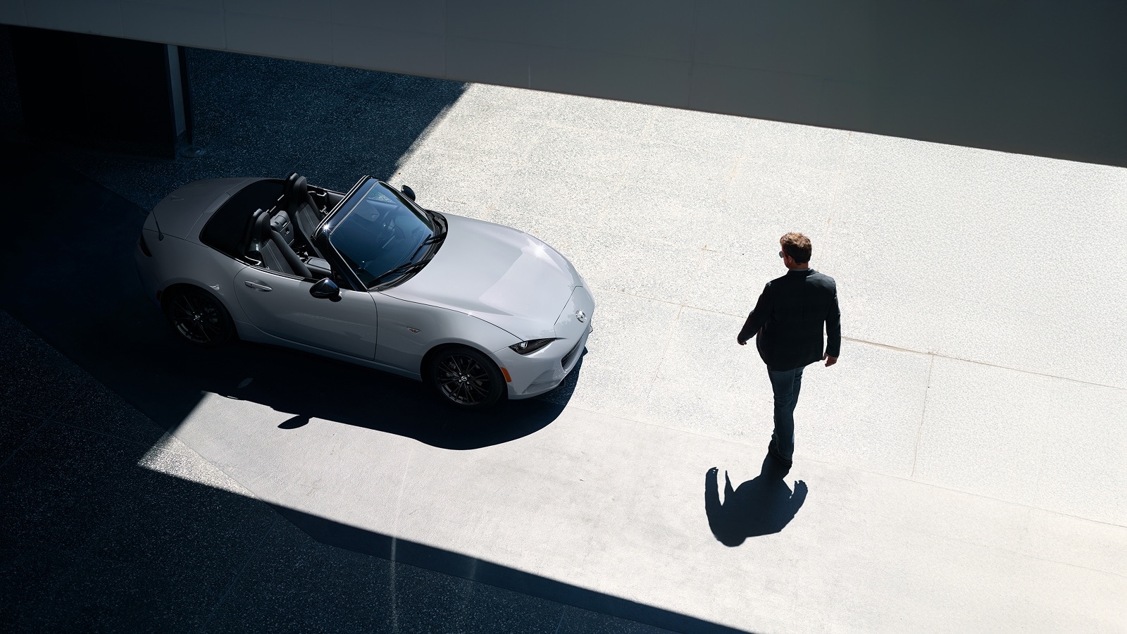 Overhead view of a 2026 Mazda MX-5 Miata with the top down, and a man
