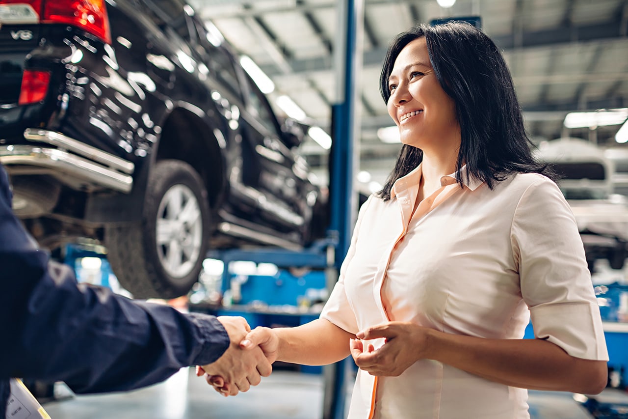 Land Rover service image with SUV, woman shaking hands with mechanic