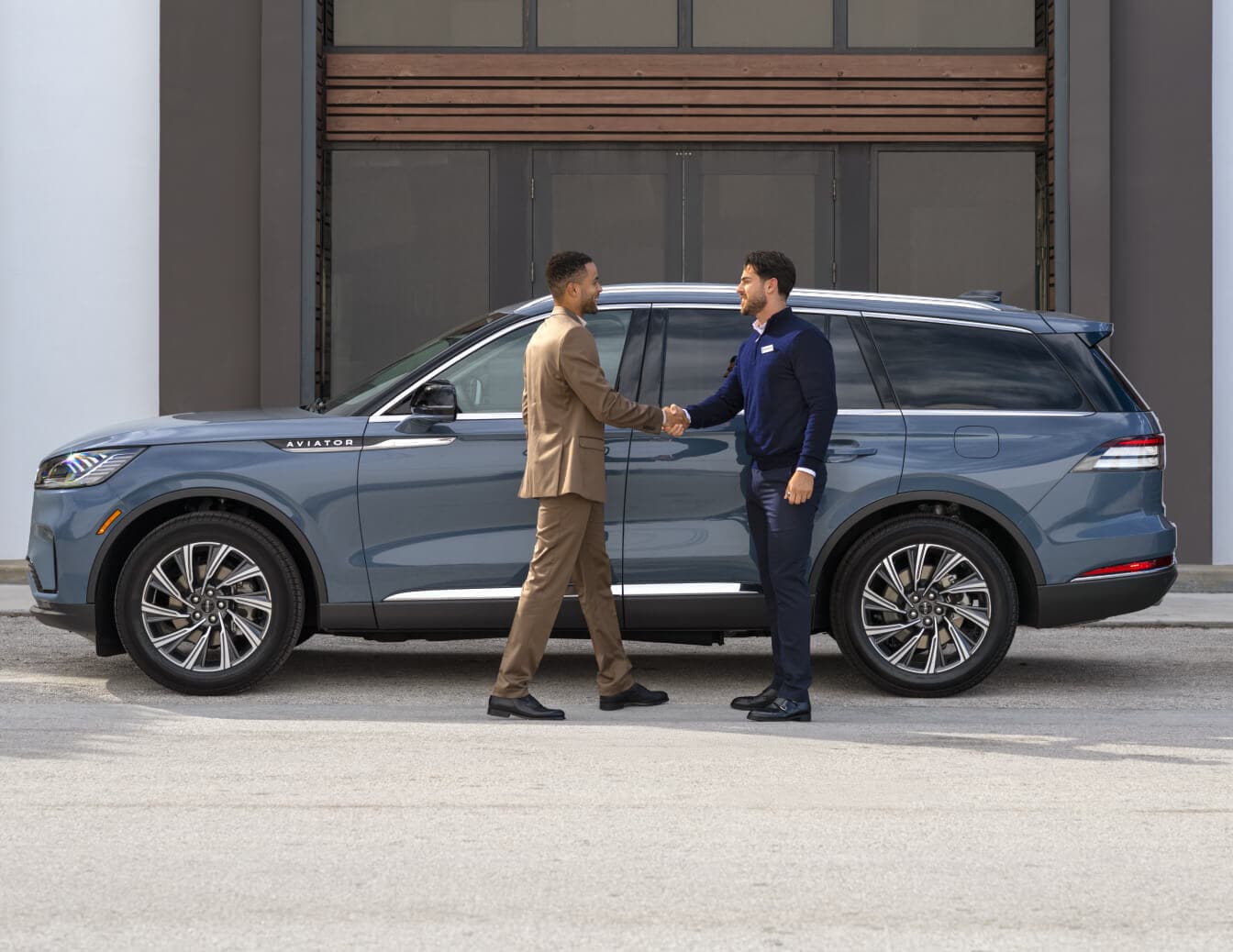 Side profile view of a Lincoln Aviator Reserve in Whisper Blue Metallic parked outside a building.