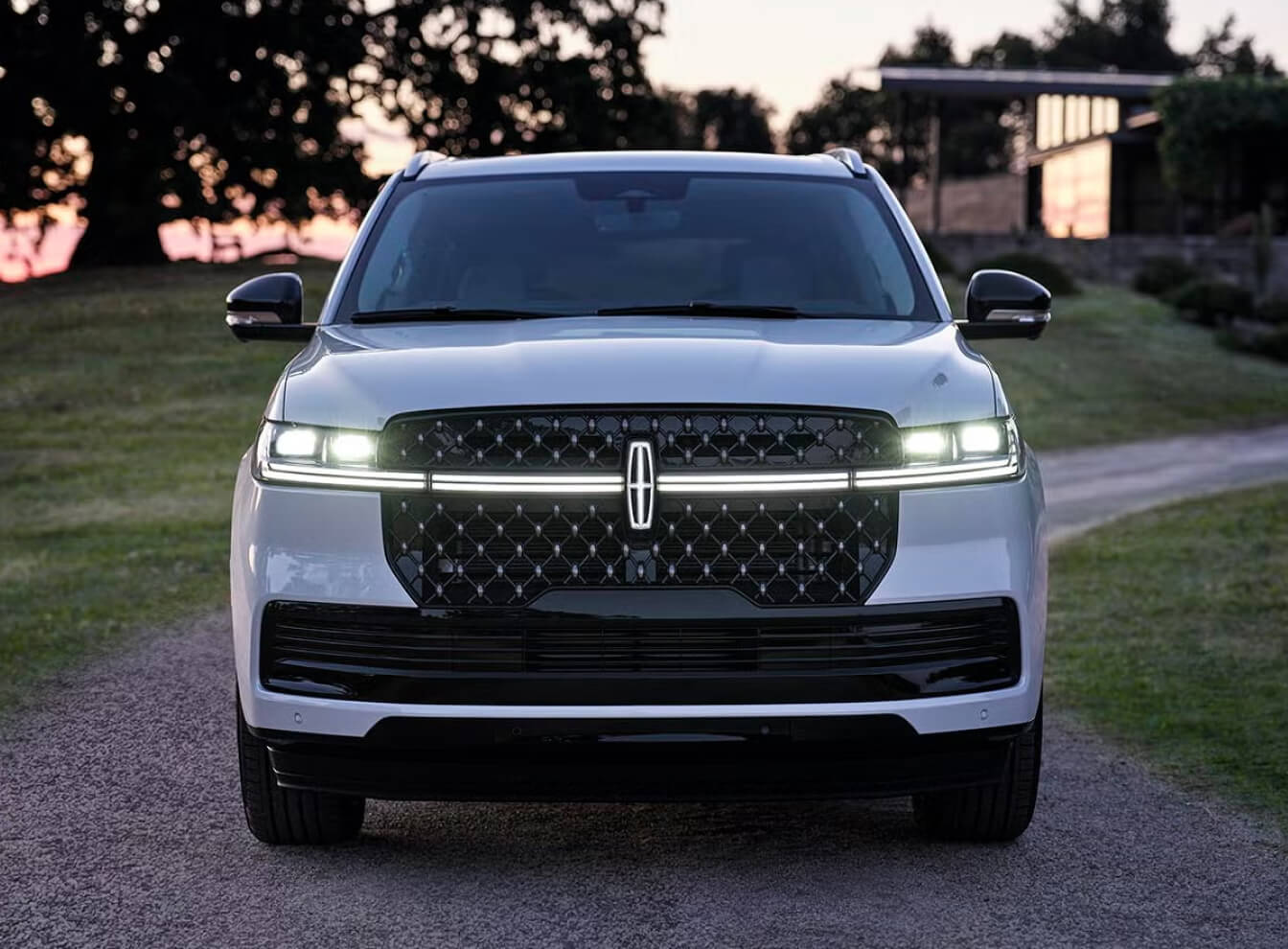 Front exterior view of a white 2027 Lincoln Navigator parked in a driveway at dusk.