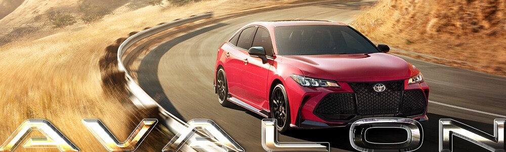Red 2019 Toyota Avalon driving on a country road by wheat fields