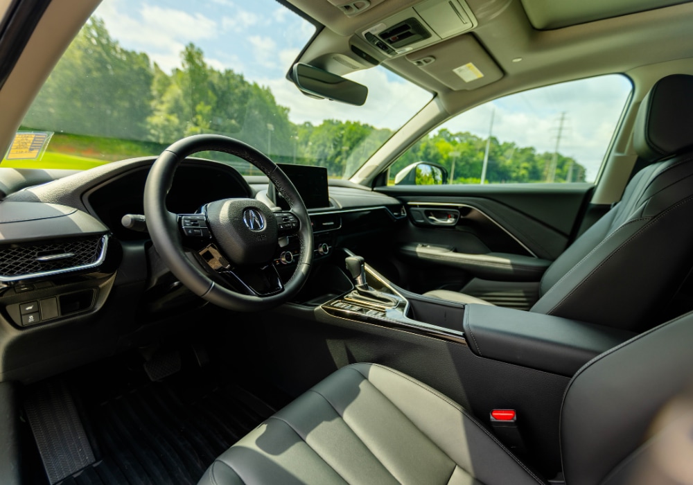 An image of the stylish interior of a new Acura ADX. The picture is taken from the driver's perspective, looking across the leather upholstery and a nine-inch screen toward the passenger seat.