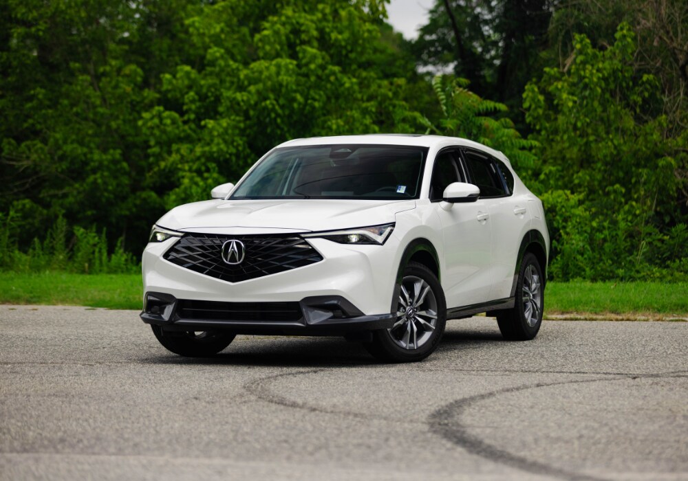 An image of a white 2025 Acura ADX in a parking lot with grass in the background.