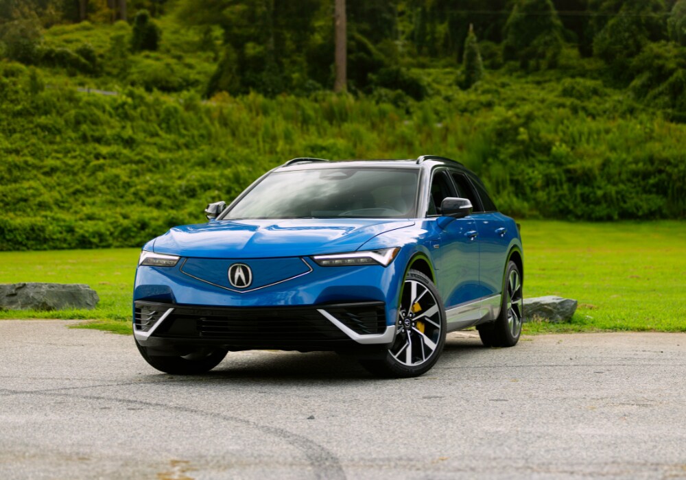 Blue Acura ZDX parked in front of a natural background. The Acura logo is visible on the front of the car