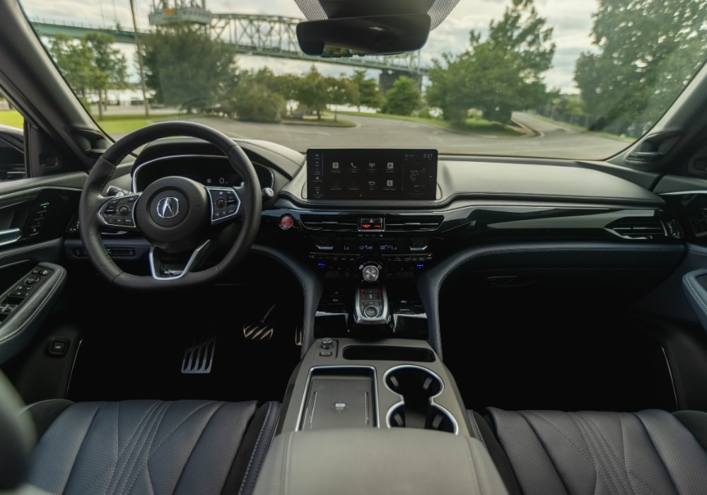 Acura MDX interior including the entire front dash. Out of the front window there is a bridge and trees
