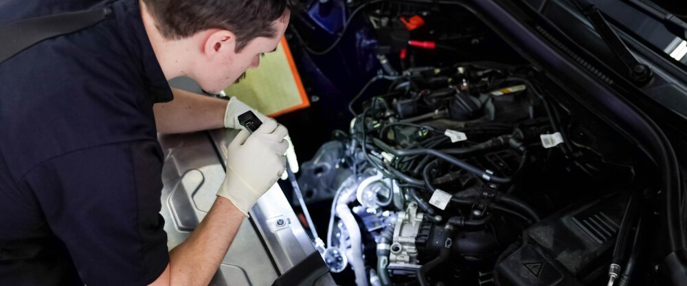 A Flow Acura service technician looks under the hood of a car