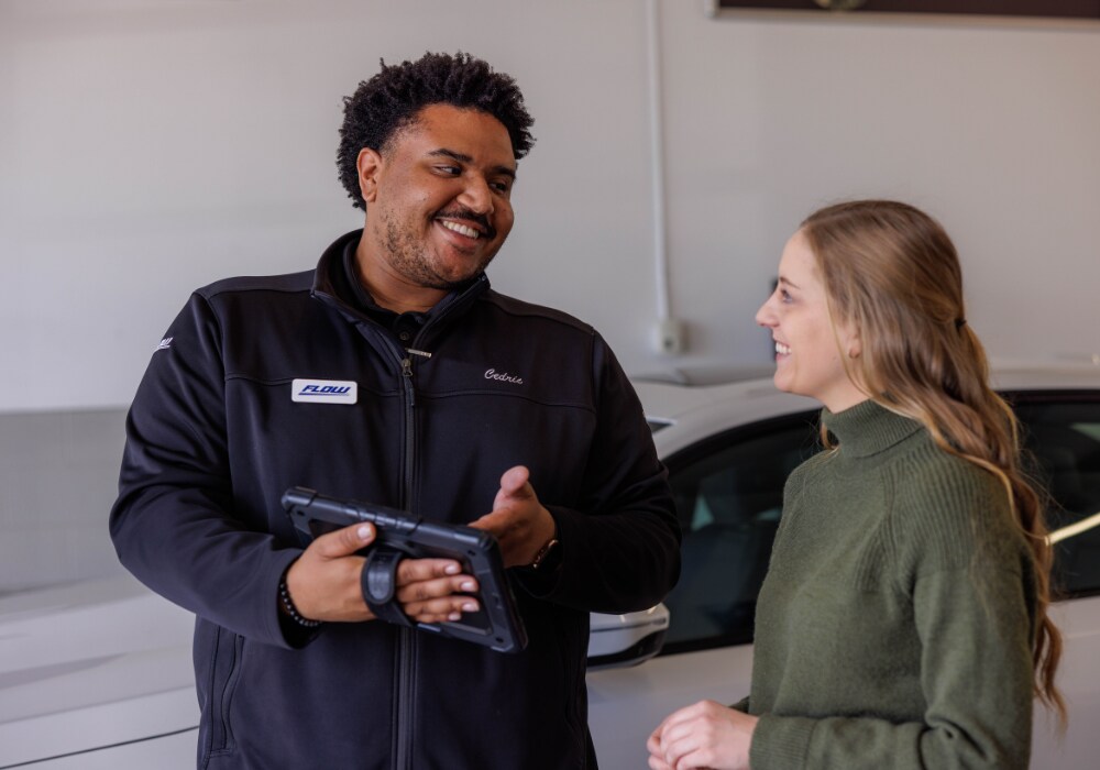 A Flow employee smiling and showing a customer something on a tablet