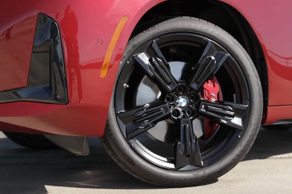 2025-bmw-x3.jpg Front tire on a 2025 BMW X3. The SUV is red and the BMW logo is visible in the center of the wheel