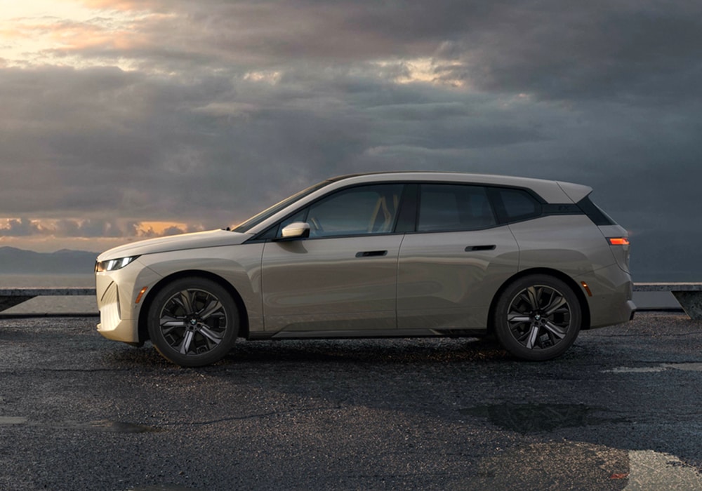 2025-bmw-ix-performance.png Driver's side view of a new BMW iX parked with a cloudy sky in the background