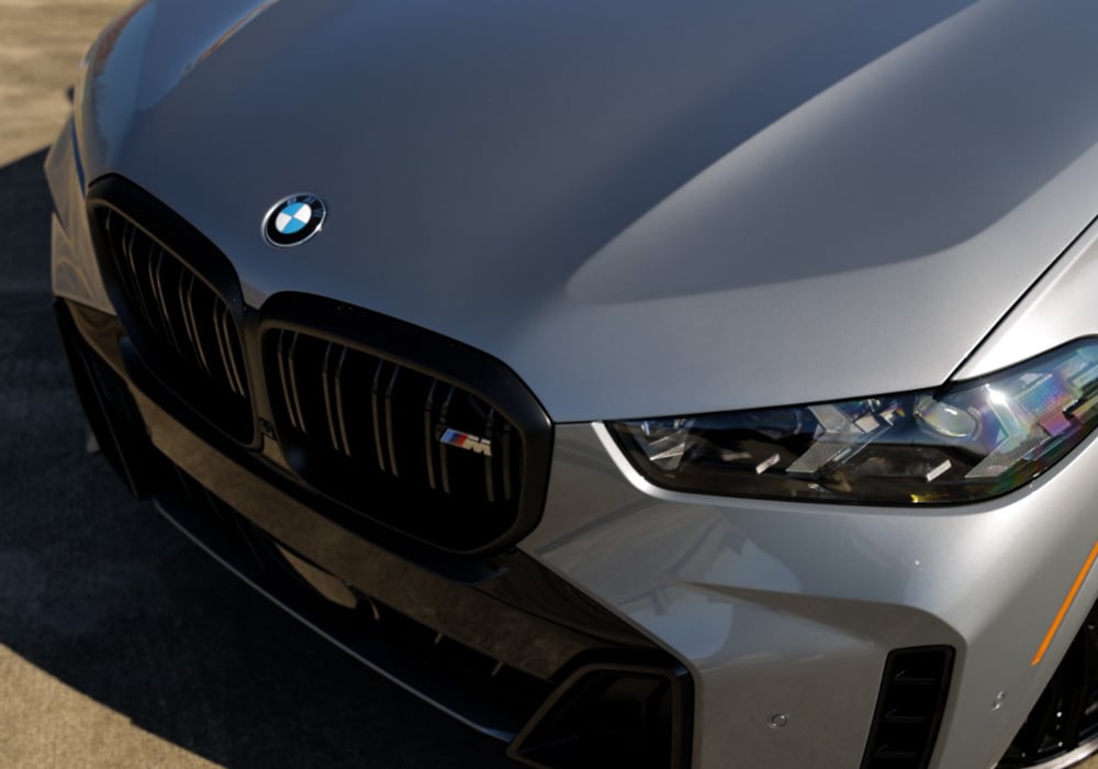 The hood and front grille of a 2025 BMW X5. The SUV is silver