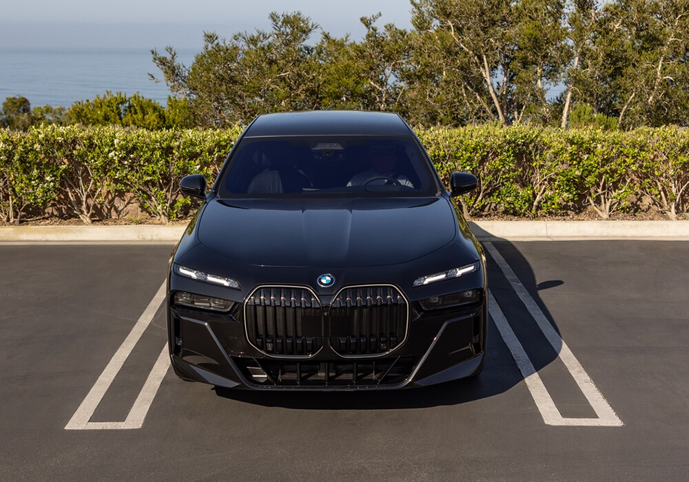 new-bmw-i7-near-me.png Front exterior view of a new BMW i7 in a parking spot with bushes in the background