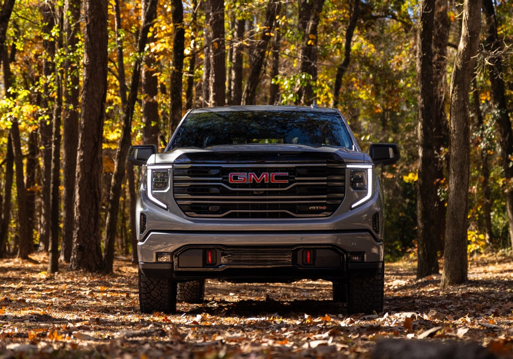 Front view of a new GMC Sierra 1500 AT4 parked in a wooded area