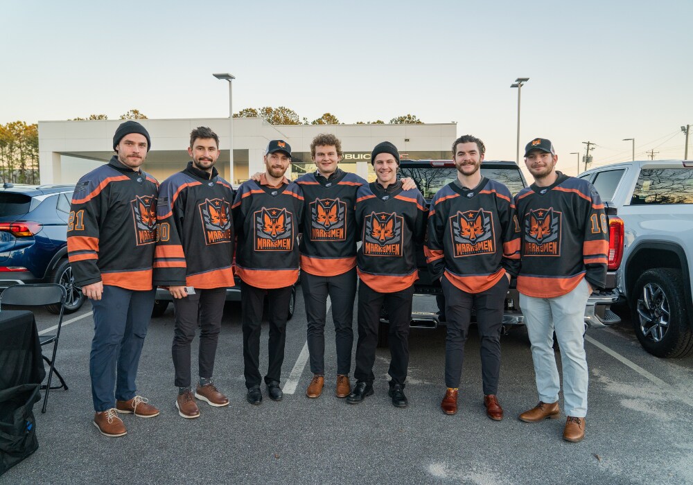 Members of the Fayetteville Marksmen hockey team standing in front of the Flow Buick GMC dealership in Fayetteville, NC