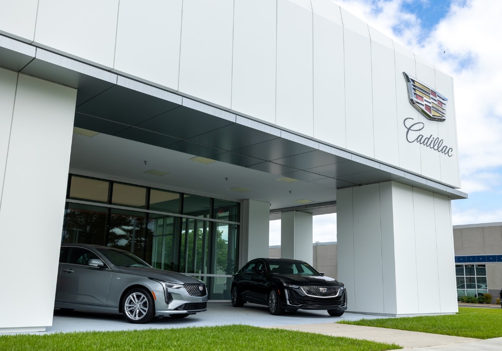 Two Cadillac SUVs parked under an awning at the Flow Cadillac of Wilmington dealership