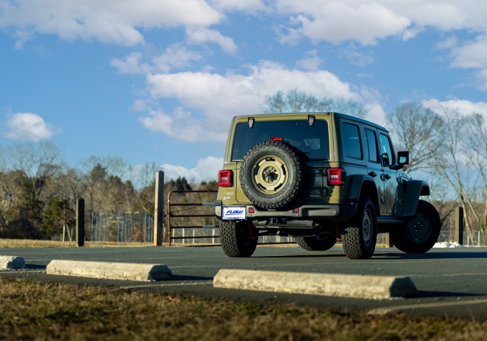 Rear of a green 2025 Jeep Wrangler for sale in Charlottesvile. The spare tire is affixed to the back of the car.