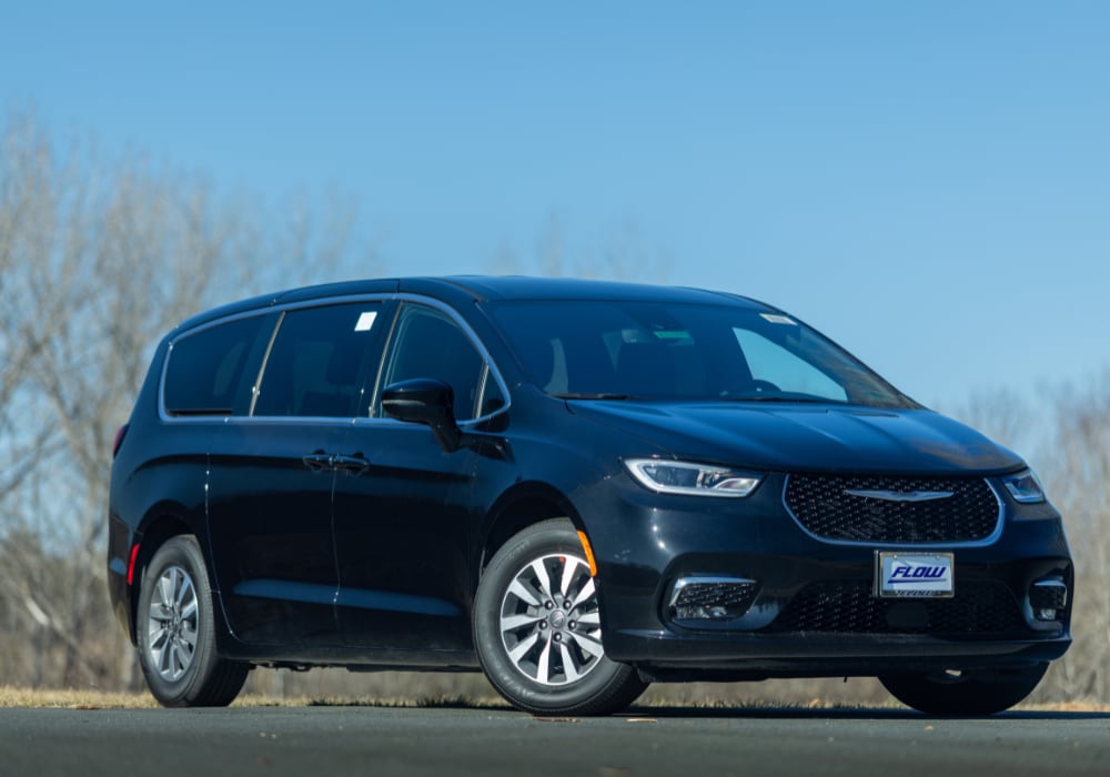 New Chrysler Pacifica parked with a blue sky in the background. The Chrysler Pacifica is black and the front of the car is angled towards the camera