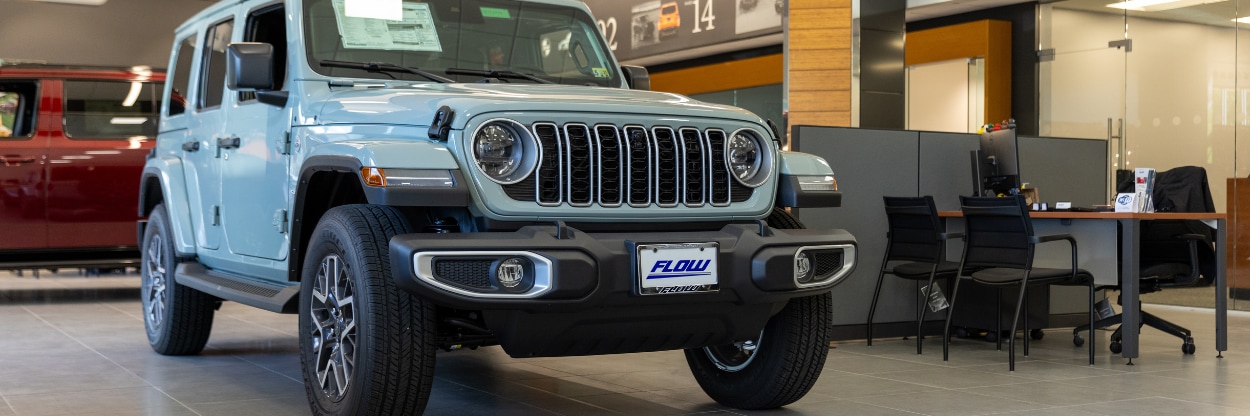Light blue Jeep Wrangler parked inside the Flow Chrysler Dodge Jeep Ram showroom in Charlottesville, VA