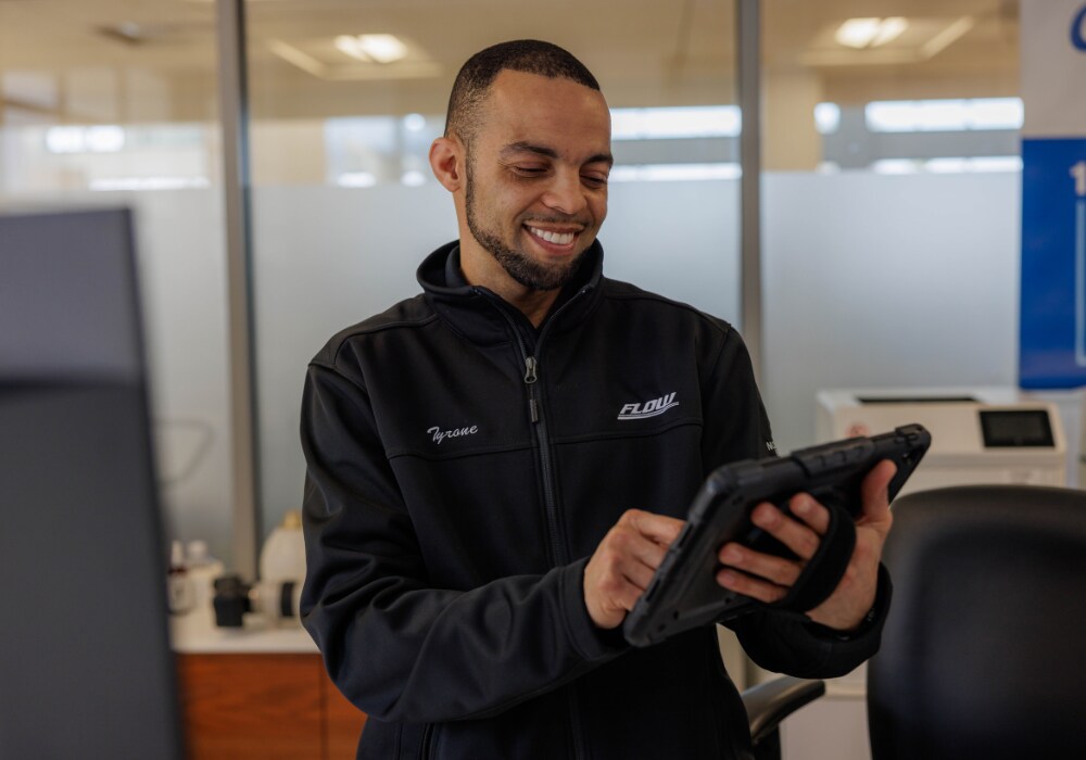 A Flow service employee smiling and using a tablet