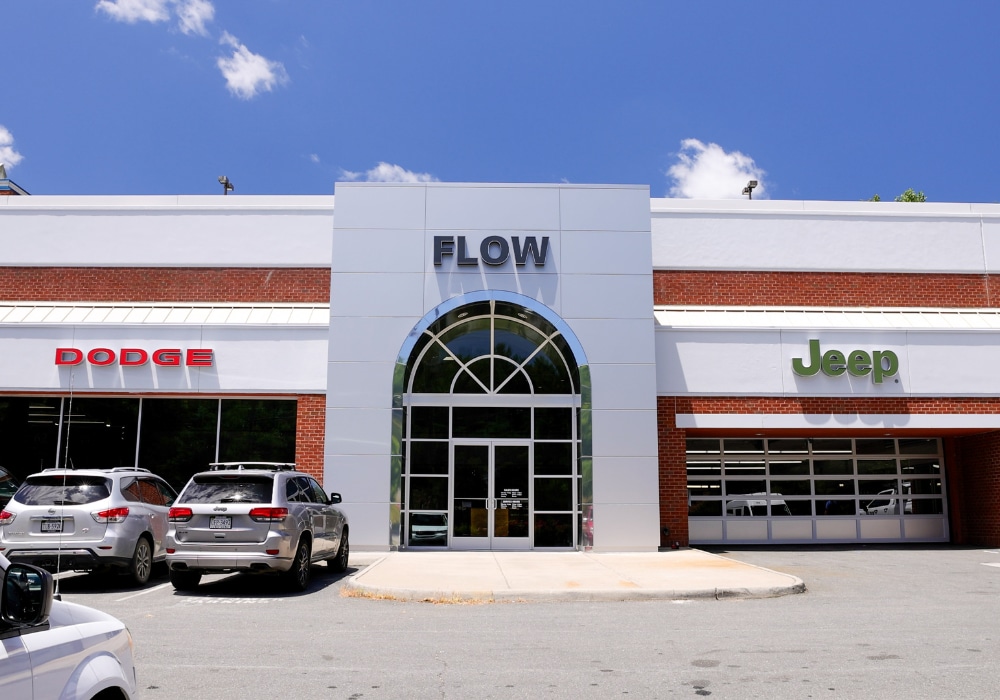 Storefront of Flow Chrysler Dodge Jeep Ram of Charlottesville dealership. Dodge and Jeep logos are visible on the front of the store