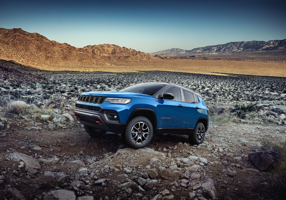Blue Jeep Compass on a rocky terrain with mountains in the background