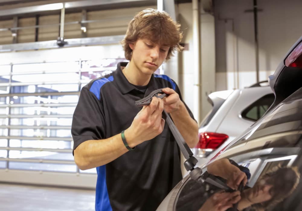 Flow service technician replacing the rear wiper blade on a vehicle inside the service center of a dealership