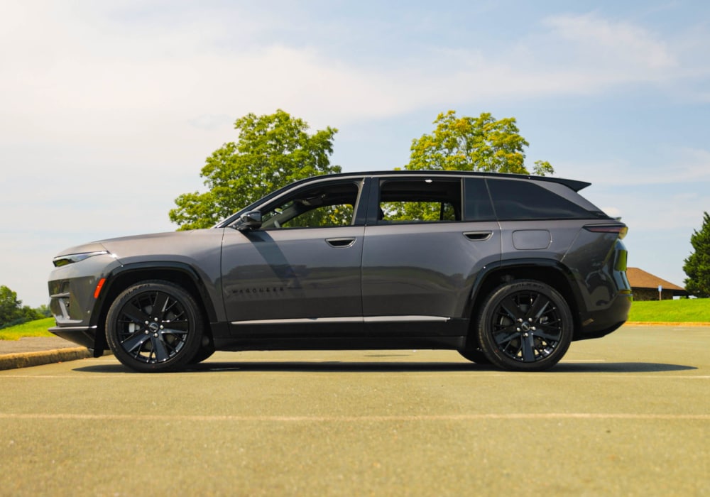 Driver's side view of 2025 Jeep Wagoneer S parked in a paved lot with trees and a blue sky in the background
