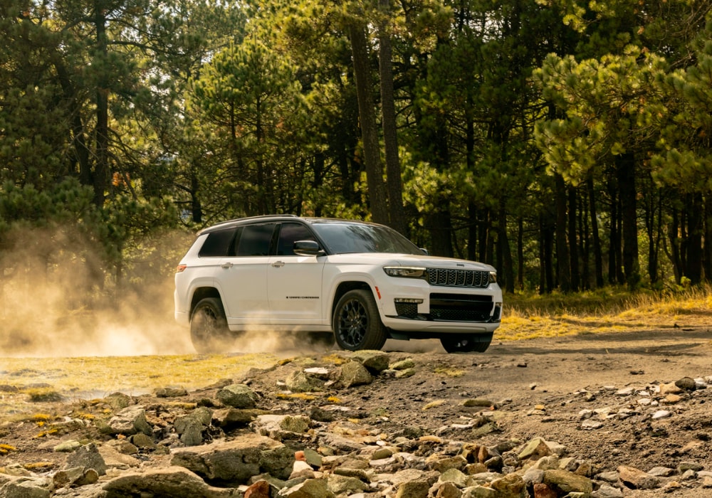 Jeep Grand Cherokee driving on a rocky path through a wooded area