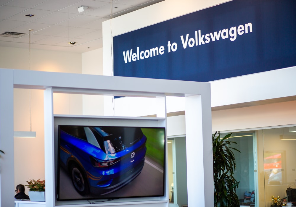 Interior of the Flow Volkswagen of Burlington dealership. There is a white and blue sign that says Welcome to Volkswagen