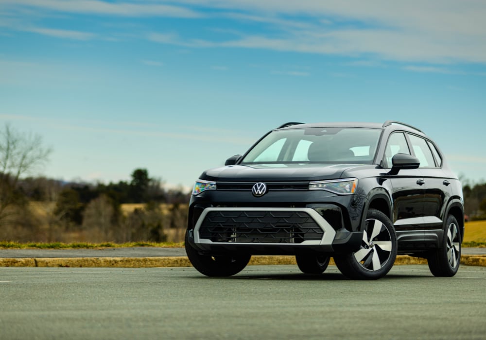 Black Volkswagen Taos parked on a paved surface with trees in the background